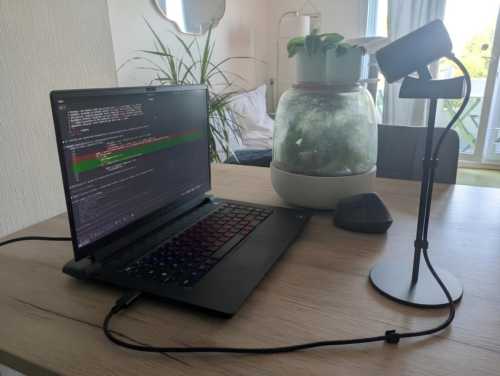 L'Alienware m15 R7 sur une table, clavier allumé, avec une Logitech C920 sur un pied à côté, braquée sur le clavier